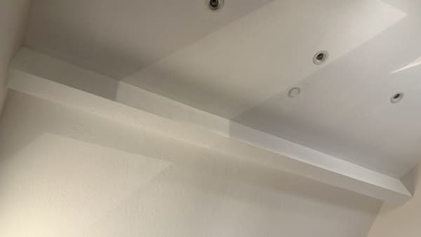 Ceiling drywall detail with smooth texture and recessed lighting in interior space